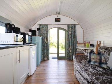 A small living area with kitchen appliances a sofa and a table with chairs at The Lamb Shack in St Teath