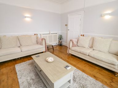 A living room with two beige sofas a wooden coffee table and a rug at Penholm in Penmaenmawr