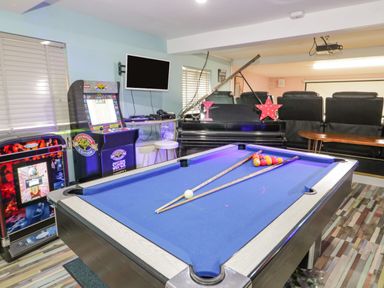 A game room with a pool table a piano arcade machines and seating at Penholm in Penmaenmawr