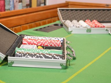 A green poker table with two open cases of poker chips and cards