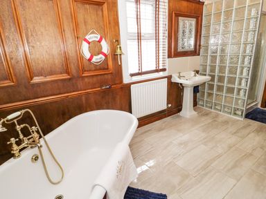 A bathroom with a bathtub a sink and a glass block shower at Penholm in Penmaenmawr