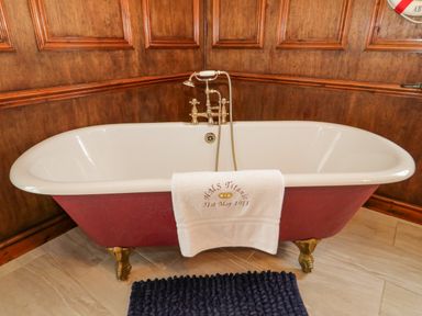A bathtub with a towel hanging over it in a bathroom with wooden paneled walls at Penholm in Penmaenmawr