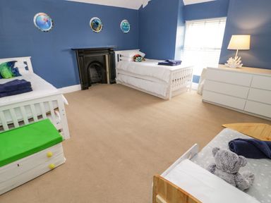 A bedroom with three beds a fireplace a white dresser and a window with blinds at Penholm Penmaenmawr