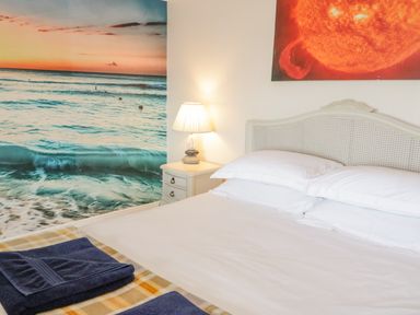 A bedroom with a bed with white bedding and pillows two framed pictures on the wall bedside table with lamp Penholm Penmaenmawr