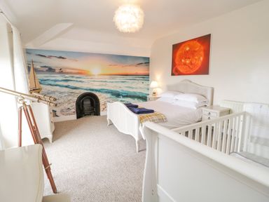 A bedroom with a bed a baby crib telescope and a wall mural of the ocean at Penholm in Penmaenmawr