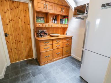 A kitchen corner with a wooden cabinet and a white refrigerator at Llety Perygl in Harlech