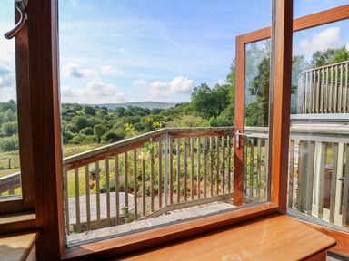 View of a wooden balcony railing with greenery and hills in the background at Plasybangor in Newport Pembrokeshire