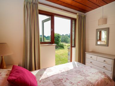 A bedroom with a bed pillow dresser mirror and an open door to a garden at Plasybangor in Newport Pembrokeshire