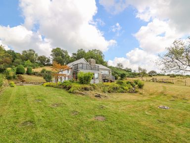 A house with a balcony surrounded by a grassy yard and trees at Plasybangor in Newport Pembrokeshire