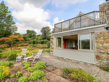 A stone house with patio chairs and plants in the garden at Plasybangor in Newport Pembrokeshire