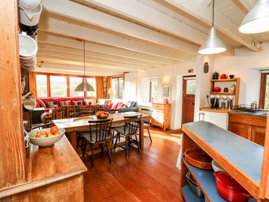 A kitchen and dining area with wooden furniture and a sitting area with sofas at Plasybangor in Newport Pembrokeshire