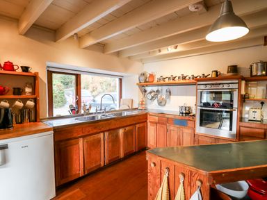 A kitchen with wooden cabinets double sink and oven at Plasybangor in Newport Pembrokeshire