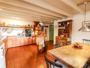 A kitchen with wooden cabinets a dining table with chairs and a wooden cupboard at Plasybangor in Newport Pembrokeshire