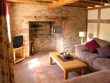 A living room with a stone wall fireplace a wooden coffee table and a sofa at Point Cottage in Preston-on-Wye near Hereford