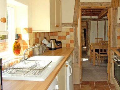 A kitchen with a sink drying rack kettle and toaster leading to a dining area at Point Cottage Preston-on-Wye near Hereford