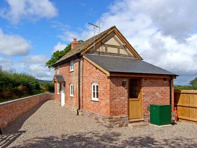 A brick house with a sloped roof driveway and a wooden door at Point Cottage in Preston-on-Wye near Hereford