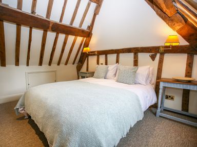 A bedroom with a double bed and wooden beams on the ceiling at Murton Cottage in Burford
