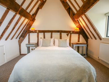 A bedroom with a double bed and bedside tables under exposed wooden beams at Murton Cottage in Burford