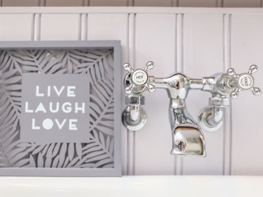 A chrome wall-mounted faucet with hot and cold handles next to a framed decorative sign saying live laugh love at Murton Cottage Burford