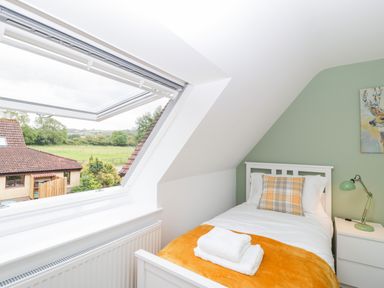 A bedroom with a single bed by a roof window and bedside table with lamp at The Forge in Shipham