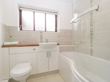 A bathroom with a toilet sink bathtub and a frosted window at The Forge in Shipham