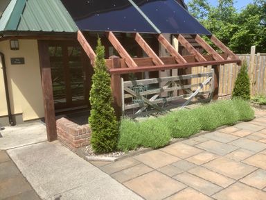 An outdoor patio area with wooden fence and green plants at The Forge in Shipham