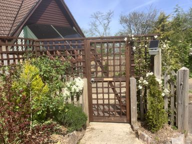 A wooden garden gate with climbing white flowers and surrounding bushes at The Forge in Shipham