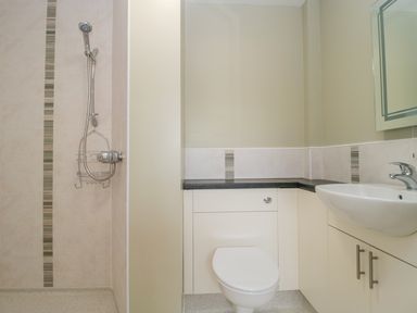 A bathroom with a shower, toilet, sink, and mirror at Mendip Cottage in Shipham