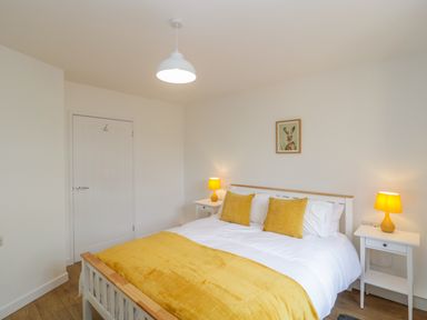 A bedroom with a white bed and yellow bedding with matching lamps on bedside tables at Mendip Cottage in Shipham