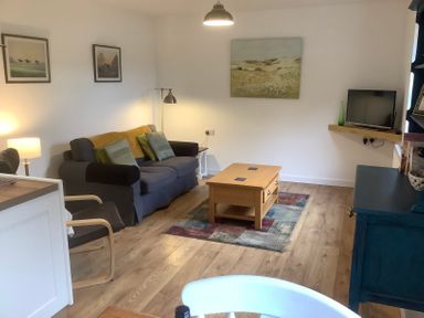 A living room with sofa armchair wooden coffee table and television at Mendip Cottage in Shipham