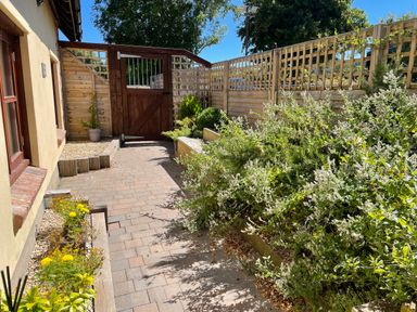 A paved garden path with plants and wooden fencing at Mendip Cottage in Shipham