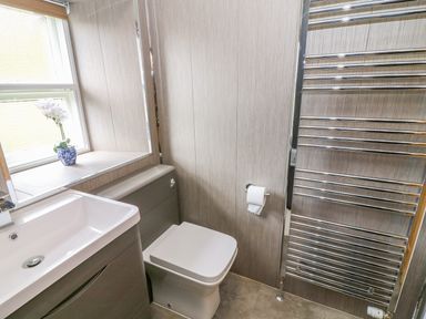 A bathroom with a sink vanity toilet paper roll and a towel radiator at Tilberthwaite Farm Cottage in Coniston