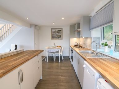 A kitchen with wooden countertops a dining table set for two and appliances at Cuckoo Cottage in Bridport