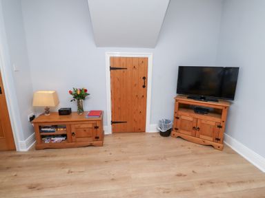 A snug with a television and wooden furniture at Hasting Dairy in North Sunderland near Seahouses