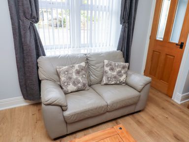 A couch with cushions and a door at Hasting Dairy North Sunderland near Seahouses