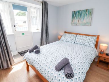 A bedroom with a double bed and door at Hasting Dairy, North Sunderland near Seahouses
