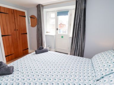 A bedroom with a bed and wooden wardrobe at Hasting Dairy in North Sunderland near Seahouses
