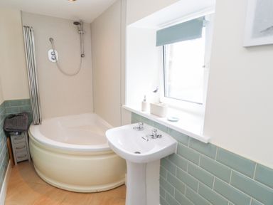A bathroom with a shower and bathtub at Hasting Dairy in North Sunderland near Seahouses