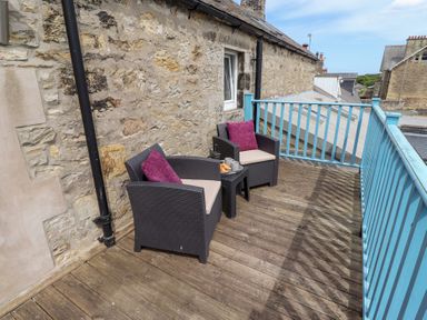 An outdoor area with chairs and a table at Hasting Dairy in North Sunderland near Seahouses