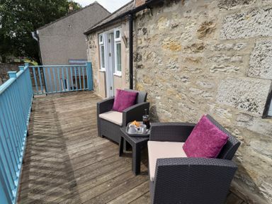 An outdoor seating area with chairs and a small table at Hasting Dairy North Sunderland near Seahouses