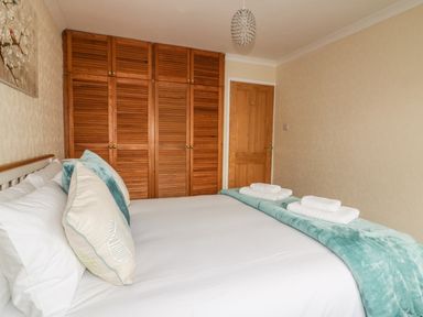 A bedroom with a bed and folded towels on a throw at Dune Haven in Goonhavern near Perranporth