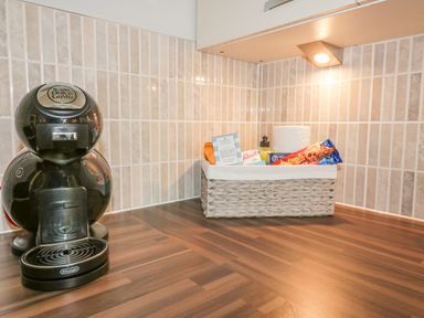 A kitchen counter with a coffee machine and a basket of snacks and paper towel at Dune Haven in Goonhavern near Perranporth