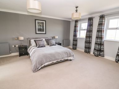 A bedroom with a double bed lamps on bedside tables framed picture on wall and two windows with curtains at Cadwgan Aberporth