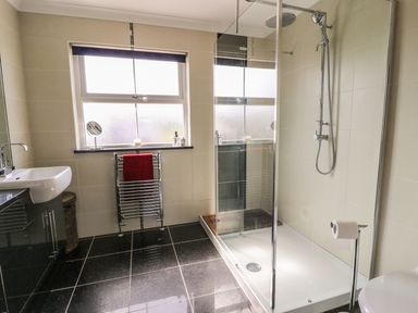 A bathroom with a walk in shower sink window and towel rail at Cadwgan in Aberporth