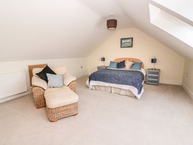 A bedroom with a bed and an armchair with ottoman at Cadwgan in Aberporth