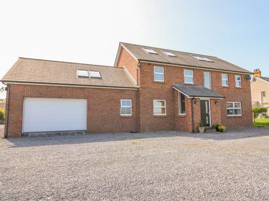 A two-story brick house with a large garage and gravel driveway at Cadwgan in Aberporth