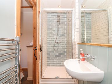 A bathroom with a shower enclosure a sink with soap dispenser and a towel radiator at Swallows Nest Morvah