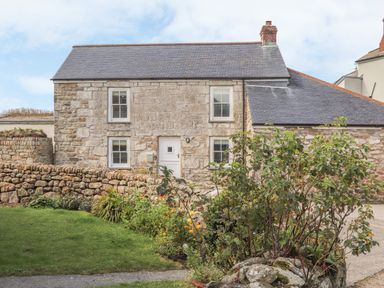 A stone house with a slate roof surrounded by a stone wall and garden in Morvah