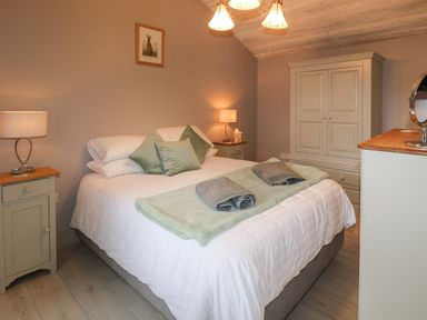 A bedroom with a bed a wardrobe two bedside tables and lamps at The Hen House in Stockwell Heath near Rugeley