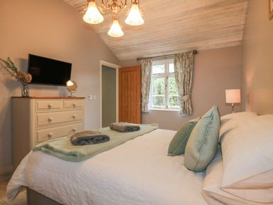 A bedroom with a bed a chest of drawers a window and a television at The Hen House in Stockwell Heath near Rugeley